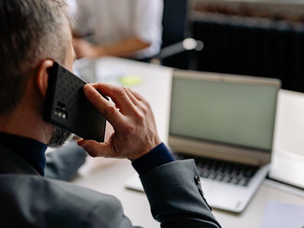 Architekt prowadzący rozmowę telefoniczną przy stanowisku pracy.
